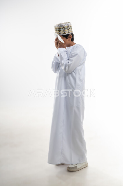 بورتريه لشاب عربي خليجي عماني يرتدي الدشداشة و الكمه ، صورة الجسم بالطول الكامل, خلفية بيضاء