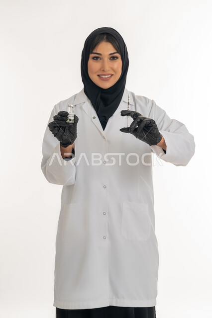 تجنب إنتشار العدوى، تحديد الحجم والكتله، اتباع اجراءات الوقاية، بورتريه لطبيبة عربية خليجة اماراتية محجبة ترتدي المعطف والكمامة الطبية تحمل بيدها حقنة وجرعة من لقاح كورونا (كوفيد -19 )، شابة سعودية ترفع كفيها للأعلى لتحجيم شيء ما، خلفية بيضاء