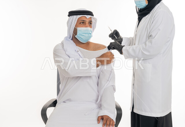 الوعي الصحي و تجنب إنتشار العدوى، اتباع اجراءات الوقاية والسلامة، تلقي التطعيم ضد فايروس كورونا، الالتزام باجراءات وزارة الصحة، بورتريه لرجل عربي خليجي اماراتي يرتدي الكندورة والغترة والكمامة الطبية يقوم بتلقي لقاح كوفيد - 19 من الطبيبة، خلفية بيضاء