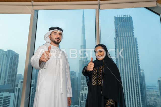 التفاهم والتعاون بين الزملاء لتحقيق أهداف الشركة، تعابير الجودة والامتياز، صورة مقربة لموظفين عربيان خليجيان يقفان باستقامة يرفعان يديهما بايماءات القبول والموافقة، بيئة العمل المريحة في شركات الامارات