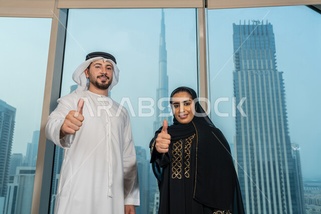 التفاهم والتعاون بين الزملاء لتحقيق أهداف الشركة، تعابير الجودة والامتياز، صورة مقربة لموظفين عربيان خليجيان يقفان باستقامة يرفعان يديهما بايماءات القبول والموافقة، بيئة العمل المريحة في شركات الامارات