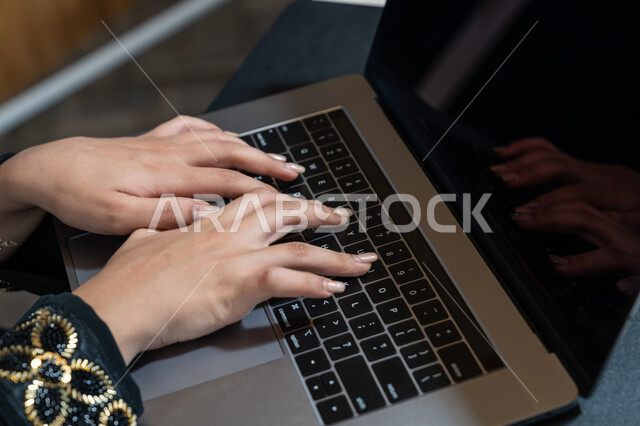 ادخال البيانات من خلال لوحة المفاتيح, تطور التكنولوجيا وإستخدام الأجهزة التقنية الحديثة, صورة مقربة ليدين امرأة عربية خليجية اماراتية ترتدي العباءة السوداء تقوم بادارة الأعمال من خلال الحاسوب المحمول، تصفح الانترنت وبرامج التواصل الاجتماعي