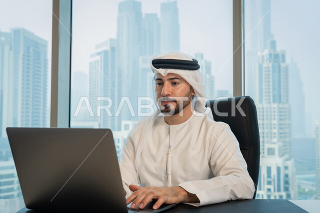 مهن ووظائف ادارية مكتبية, تصفح الانترنت وبرامج التواصل الاجتماعي, تطور التكنولوجيا وإستخدام الأجهزة التقنية الحديثة, صورة لرجل عربي خليجي اماراتي يرتدي الزي التقليدي ويقوم بادارة الأعمال من خلال جهاز الحاسوب المحمول