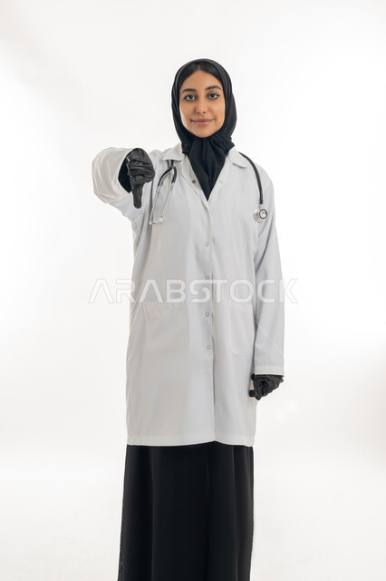 العمل في القطاع الصحي، تقديم المساعده الطبية للمرضى, بورتريه لطبيبة عربية خليجية اماراتية محجبة ترتدي المعطف الطبي الأبيض وسماعة الفحص بإيماءات يدين تدل على عدم الاعجاب, مفهوم الطب والرعاية الصحية, خلفية بيضاء