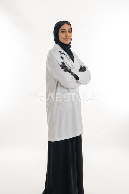 Providing medical assistance to patients, working in health centers and hospitals, portrait of an Arab Gulf Emirati female doctor wearing a white medical coat and an examination stethoscope, concept of medicine and health care, full-length body image, white background