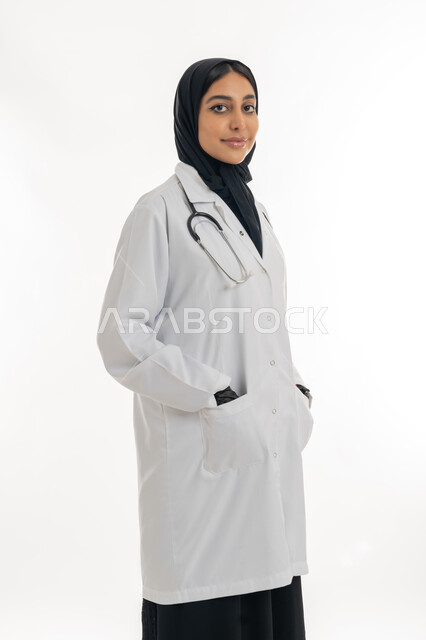 مهن ووظائف نسائية, تقديم المساعده الطبية للمرضى, شابة سعودية تقوم بالعمل في المراكز والمستشفيات, بورتريه لطبيبة عربية خليجية اماراتية ترتدي المعطف الطبي الأبيض وسماعة الفحص تنظر إلى الكاميرا بايماءات الثقة بالنفس, مفهوم الطب والرعاية الصحية, خلفية بيضاء