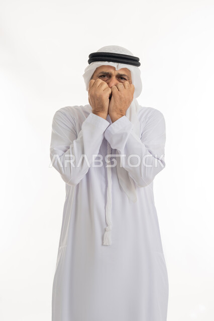 التعبير عن خيبة الأمل والصدمة، وضع اليدين على الوجه بتعابير الخوف والمفاجأة، بورتريه مقرب لرجل عربي خليجي إماراتي كبير بالسن يرتدي الكندورة الإماراتية التقليدية والغترة يغطي وجهه بيديه بإيماءات الذهول، خلفية بيضاء