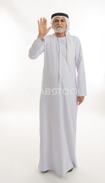 طلب التوقف عن فعل شيء ما، فتح الكف ورفعها في الهواء بتعابير الحزم والنهي، بورتريه لرجل عربي خليجي إماراتي كبير بالسن يرتدي الغترة والكندورة الإماراتية يرفع يده بإيماءات الغضب، الجسم بالطول الكامل، خلفية بيضاء