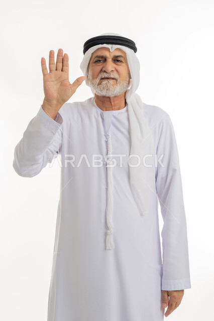 فتح الكف ورفعها في الهواء بتعابير الحزم والنهي، طلب التوقف عن فعل شيء ما، بورتريه مقرب لرجل عربي خليجي إماراتي كبير بالسن يرتدي الغترة والكندورة الإماراتية يرفع يده بإيماءات الغضب، خلفية بيضاء