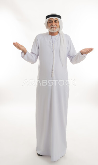 الوقوف والنظر إلى الكاميرا بعلامات الاستفهام, فتح الكفين ورفعهما في الهواء بتعابير الحيرة وعدم المعرفة، بورتريه لرجل كبير بالسن عربي خليجي إماراتي يرتدي الغترة والكندورة يرفع يديه بإيماءات التساؤل، الجسم بالطول الكامل، خلفية بيضاء