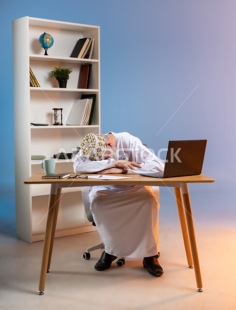 النوم على طاولة العمل، ايماءات النعاس والتعب والإرهاق، استخدام التقنيات الحديثة المتطورة في الحياة العملية، بورتريه لرجل كبير السن عربي خليجي عماني يرتدي الدشداشة والكمة يقوم بأخذ قسط من الراحة, خلفية ملونة