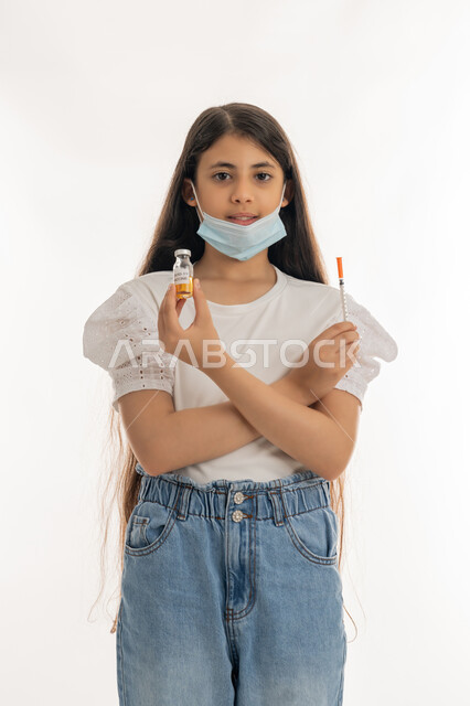 تجنب إنتشار العدوى، مفهوم الوعي الصحي، بورتريه لفتاة عربية خليجية إماراتية ترتدي الكمامة تحمل بيدها ابرة وجرعة من لقاح فايروس كورونا، الحماية من الأمراض والحفاظ على السلامة، اتباع اجراءات وزارة الصحة الوقائية، التطعيم الأمن لكوفيد19، خلفية بيضاء