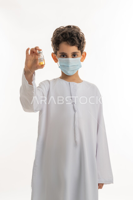تجنب إنتشار العدوى، اتباع اجراءات وزارة الصحة الوقائية، مفهوم الوعي الصحي، الحماية من الأمراض والحفاظ على السلامة، التطعيم الآمن لكوفيد19، بورتريه لولد عربي خليجي إماراتي يرتدي الكندورة والكمامة يحمل بيده جرعة من لقاح فايروس كورونا، خلفية بيضاء