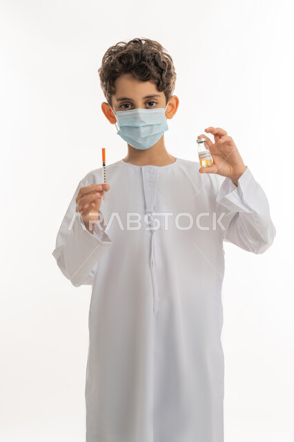 تجنب إنتشار العدوى، اتباع اجراءات وزارة الصحة الوقائية، مفهوم الوعي الصحي، الحماية من الأمراض والحفاظ على السلامة، التطعيم الآمن لكوفيد19، بورتريه لولد عربي خليجي إماراتي يرتدي الكندورة والكمامة يحمل بيده ابرة وجرعة من لقاح فايروس كورونا، خلفية بيضاء