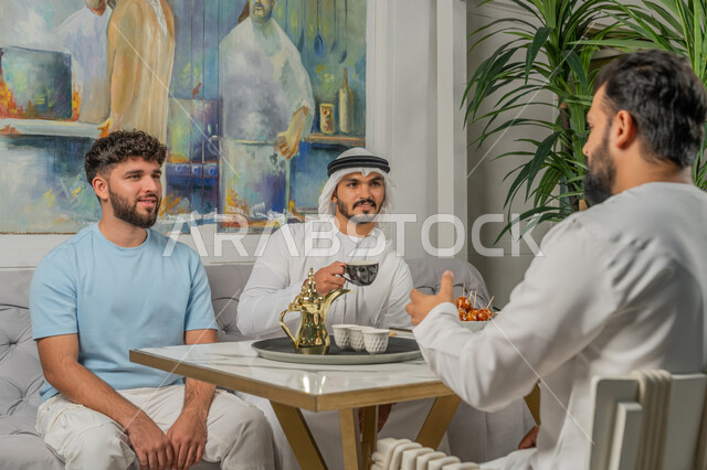 النقاشات والحوارات في الأجواء الهادئة، علاقات اجتماعية ناجحة بين الأشخاص، قضاء أوقات ممتعة مع الأصدقاء، رجل عربي خليجي اماراتي يرتدي الكندورة والغترة البيضاء يجلس مع أصدقائه في إحدى المقاهي الراقية يشربون القهوة ويتناولون الحلويات، تعابير السعادة والسرور