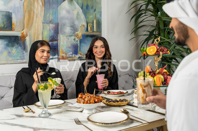 قضاء أوقات ممتعة مع الأصدقاء، النقاش والحوار في الأجواء الهادئة، مشاركة المشروبات الباردة والحلويات والفواكه، بناء علاقات اجتماعية ناجحة بين الأشخاص، صورة مقربة لزملاء عربيين خليجيين اماراتيين مبتسمين يجلسون في إحدى المقاهي الراقية بتعابير السعادة والسرور