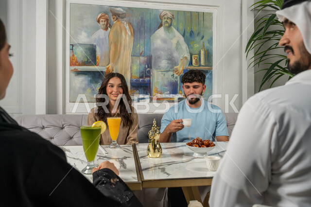 الاستمتاع مع الأصدقاء، النقاشات والحوارات في الأجواء الهادئة، مشاركة المشروبات الباردة والقهوة والحلويات، بناء علاقات اجتماعية ناجحة بين الأشخاص، صورة مقربة لزملاء عربيين خليجيين اماراتيين مبتسمين يجلسون في إحدى المقاهي الراقية بتعابير السعادة والسرور