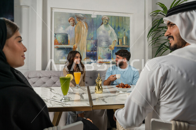 قضاء أوقات ممتعة مع الأصدقاء، النقاشات والحوارات في الأجواء الهادئة، مشاركة المشروبات الباردة والقهوة والحلويات، بناء علاقات اجتماعية ناجحة بين الأشخاص، صورة مقربة لزملاء عربيين خليجيين اماراتيين مبتسمين يجلسون في إحدى المقاهي الراقية بتعابير السعادة والسرور