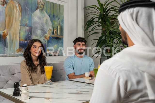 بناء علاقات اجتماعية ناجحة بين الأشخاص، النقاشات والحوارات في الأجواء الهادئة، مشاركة المشروبات الباردة والقهوة، قضاء أوقات ممتعة مع الأصدقاء، صورة مقربة لزملاء عربيين خليجيين اماراتيين يجلسون في إحدى المقاهي الراقية بتعابير السعادة والسرور