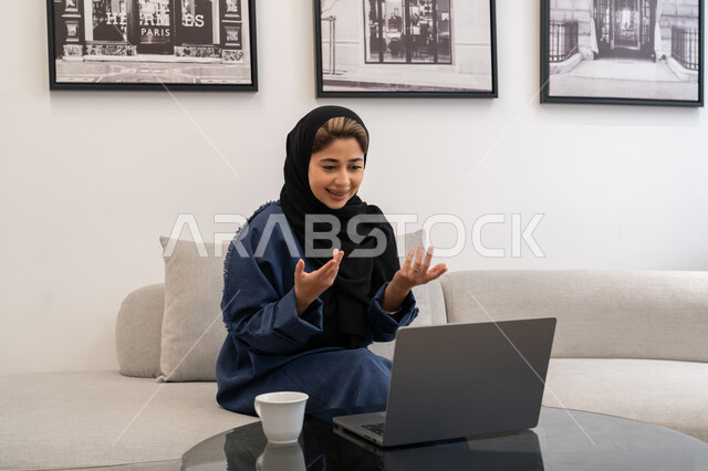 Expressions of focus and integration, integrating technology into work, Saudi women's jobs and professions, remote business management, a Saudi Arabian Gulf woman wearing an abaya and hijab using a laptop, completing tasks at home, an Emirati woman using modern and advanced devices and technologies