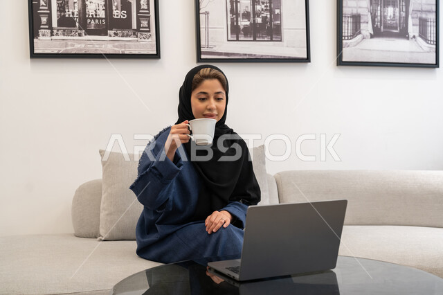 Gestures of focus and integration, integrating technology into work, Saudi women's professions and jobs, remote business management, a Saudi Arabian Gulf woman wearing an abaya and hijab using a laptop, completing tasks at home, an Emirati woman using modern and advanced devices and technologies