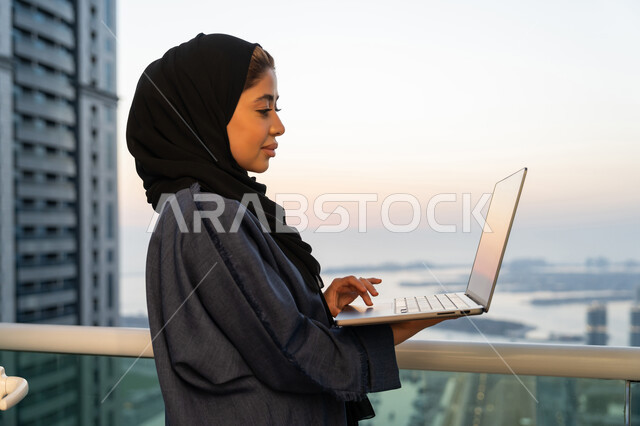 ايماءات التركيز والاندماج، دمج التكنولوجيا بالعمل، مهن ووظائف سعودية نسائية، ادارة الأعمال عن بعد، إمرأة عربية خليجية سعودية ترتدي العباءة والحجاب تستخدم الحاسوب المحمول، إنجاز المهام في المنزل، سيدة اماراتية تقوم باستخدام الأجهزة والتقنيات الحديثة والمتطورة