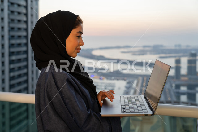 ايماءات التركيز والاندماج، دمج التكنولوجيا بالعمل، مهن ووظائف سعودية نسائية، ادارة الأعمال عن بعد، إمرأة عربية خليجية سعودية ترتدي العباءة والحجاب تستخدم الحاسوب المحمول، إنجاز المهام في المنزل، سيدة اماراتية تقوم باستخدام الأجهزة والتقنيات الحديثة والمتطورة