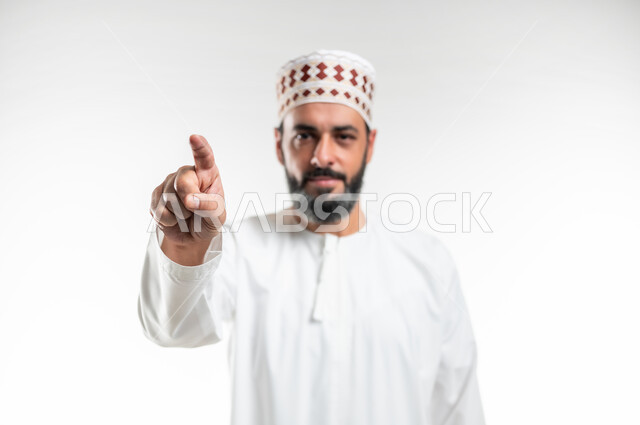 Feeling annoyed and wanting revenge, asking to stop doing wrong, accusing, reprimanding and blaming, close-up portrait of an Arab Gulf Omani man wearing a dishdasha and a sleeve raising his index finger forward to identify someone (you), white background