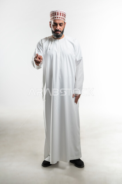 اشارات تحدد هذا المكان (هنا)، تعابير التحديد والتأكيد, الاشارة إلى شيء ما، بورتريه لرجل عربي خليجي عماني يرتدي الدشداشة والكمه يقف باستقامة و يشير بأصبعين للإختيار، صورة الجسم بالطول الكامل، خلفية بيضاء