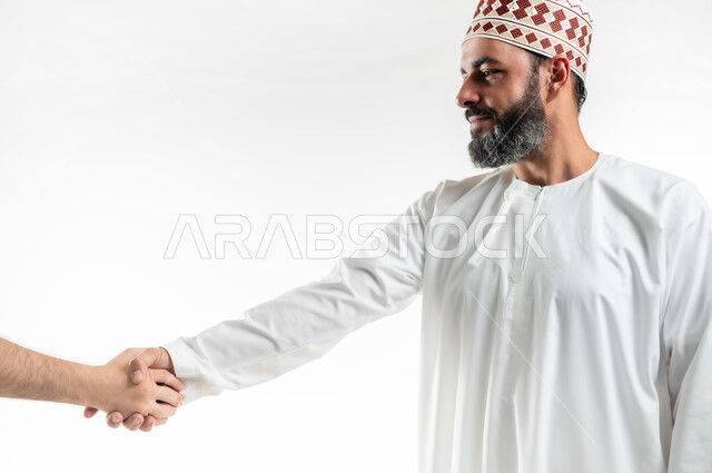 الاتفاق على استراتيجيات العمل و المشاريع التجارية، الترحيب و السلام و إلقاء التحية، بورتريه مقرب لرجل عربي خليجي عماني يرتدي الدشداشة و الكمه يقوم بالمصافحة، بناء علاقات و تكوين صداقات جديدة، خلفية بيضاء