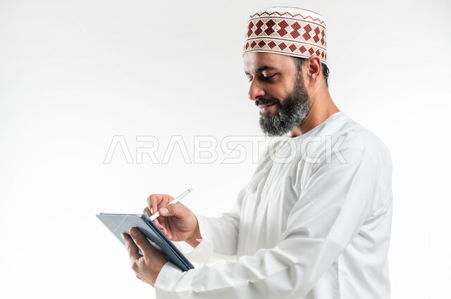 المحادثة مع الأهل والأصدقاء، استعمال التكنولوجيا و التقنيات الحديثة, بورتريه مقرب لرجل عربي خليجي عماني يرتدي الدشداشة والكمة يقوم بالكتابة على جهاز التابلت، تصفح برامج التواصل الاجتماعي، تطبيقات وبرامج الأجهزة اللوحية، خلفية بيضاء