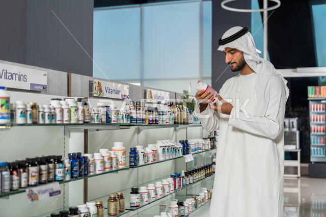 تفقد المنتجات والأدوات الطبية، رجل عربي خليجي اماراتي يرتدي الغترة والكندورة البيضاء يبحث داخل الصيدلية ويختار بعض المستلزمات، طلب الادوية الموجودة في الوصفة الطبية، شراء الادوية والعقاقير الطبية، الاستفادة من الخدمات الصحية
