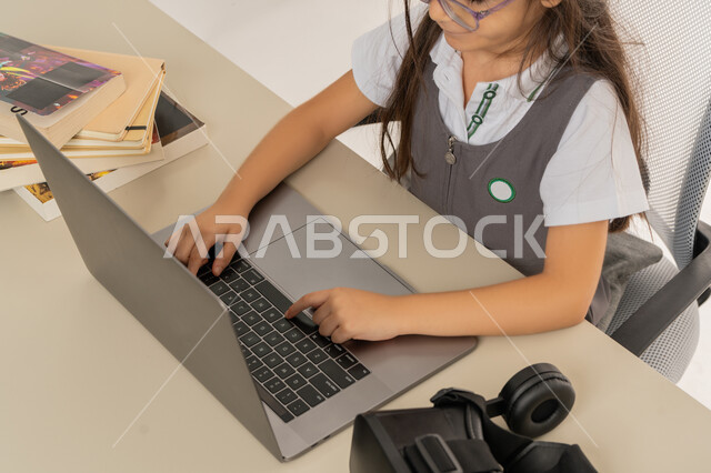 مفهوم المذاكره والمثابره على التقدم والنجاح، بورترية مقرب لتلميذة خليجية عربية إماراتية ترتدي اليونيفورم المدرسي وتتابع حصص الاونلاين عبر الحاسوب، طالبه مجتهده متفوقه تدرس عن بعد عبر الانترنت، الاستعداد للإمتحانات والاختبارات المدرسيه، خلفية بيضاء