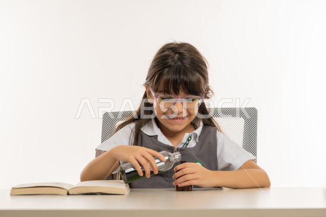 Acquisition of knowledge through modern practical experiments, a close-up portrait of an Arab Gulf Emirati student in an advanced educational environment, a Saudi schoolgirl doing a chemical experiment in the school laboratory, creativity and educational