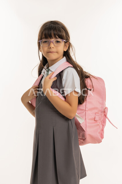 عدم الرغبة في الذهاب للمدرسة, موسم العوده إلى المدارس، التجهيز لبداية عام دراسي جديد, بورتريه من الجانب لطالبة عربيه خليجية اماراتية ترتدي الزي المدرسي وتحمل الحقيبة المدرسية, تلميذه  تشعر بالإرهاق والانزعاج, خلفية بيضاء.
