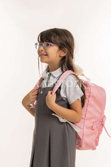 تلميذه مجتهده ومتميزه, إيماءات تدل على الحماس والسعادة، الرغبة في طلب العلم، موسم العوده للمدارس, التهيئة والتجهيز لبداية العام الدراسي, بورتريه لطالبة عربية خليجية اماراتية ترتدي اليونيفورم الخاص وتحمل الحقيبة المدرسية, خلفية بيضاء.