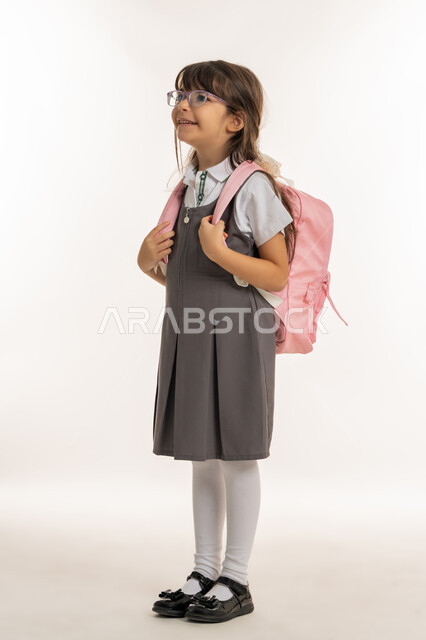 التهيئة والتجهيز لبداية العام الدراسي, بورتريه لطالبة عربية خليجية اماراتية ترتدي اليونيفورم الخاص وتحمل الحقيبة المدرسية, تلميذه مجتهده ومتميزه, إيماءات تدل على الحماس والسعادة، الرغبة في طلب العلم، موسم العوده للمدارس, خلفية بيضاء.