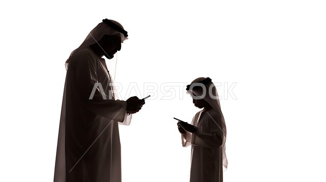 التسوق الالكتروني وتدوين الملاحظات، بورتريه  صورة ظلية لرجل عربي خليجي سعودي يعلم ابنه إستخدام جهاز التابلت، تطور التكنولوجيا واستخدام اجهزة تقنية حديثة ، خلفية بيضاء