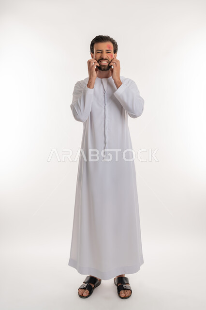 المشاكل الصحية والتهجيات، الإصابة بالحساسية الجلدية, بثور منتشرة على بشرة الوجه, بورتريه لرجل عربي خليجي اماراتي يرتدي الكندورة يقوم بالحك بإيماءات الإنزعاج والتعب, الشعور بالأوجاع والالام, صورة لكامل الجسم، خلفية بيضاء