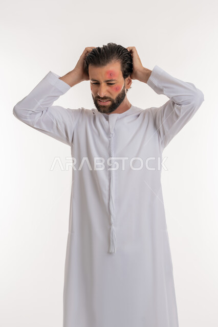تعابير التوتر والانزعاج، الطفح الجلدي والأمراض المعدية, بورتريه لشاب عربي خليجي اماراتي يرتدي الكندورة يضع يديه على رأسه بايماءات القلق, المشاكل الصحية وتهيجات الجلد, بثور منتشرة على بشرة الوجه, الإصابة الجلدية وفرط التحسس, خلفية بيضاء