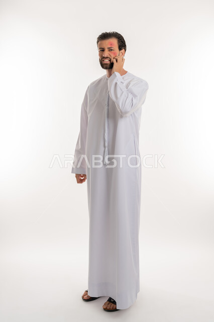 Infectious diseases and rashes, need to visit a doctor and receive treatment, portrait of a young Arab Gulf Emirati man wearing a kandura scratching with gestures of discomfort, skin irritations and health problems, pimples spread on the skin of the face, hypersensitivity and skin infection, full body image, white background