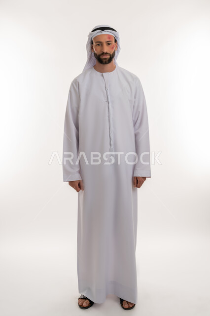 النظر الى الكاميرا بتعابير التعب والارهاق، المشاكل الصحية والتهجيات، الإصابة بالحساسية الجلدية, بثور منتشرة على بشرة الوجه, بورتريه لرجل عربي خليجي اماراتي يرتدي الكندورة والغترة يقف باستقامة, الشعور بالأوجاع والالام, خلفية بيضاء