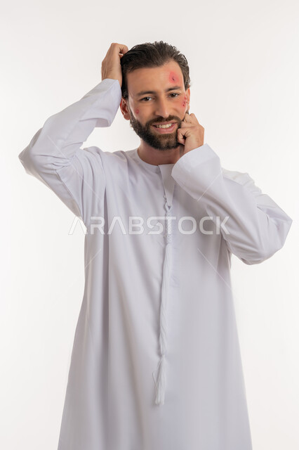 تهيجات الجلد والمشاكل الصحية, الأمراض المعدية والطفح الجلدي, الحاجة لزيارة الطبيب وتلقي العلاج, بورتريه لشاب عربي خليجي اماراتي يرتدي الكندورة يقوم بالحك بإيماءات الإنزعاج, بثور منتشرة على بشرة الوجه, فرط التحسس والإصابة الجلدية, خلفية بيضاء