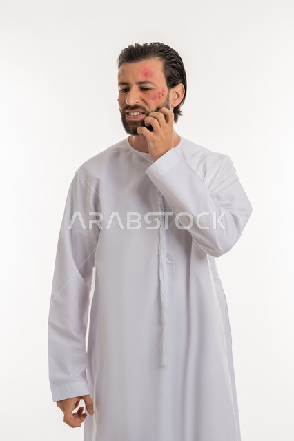 الشعور بالأوجاع والالام, المشاكل الصحية والتهجيات، الإصابة بالحساسية الجلدية, بثور منتشرة على بشرة الوجه, بورتريه لرجل عربي خليجي اماراتي يرتدي الكندورة يقوم بالحك بإيماءات الإنزعاج والتعب, خلفية بيضاء