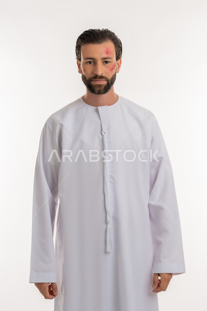 النظر الى اكاميرا بتعابير التعب والارهاق، المشاكل الصحية والتهجيات، الإصابة بالحساسية الجلدية, بثور منتشرة على بشرة الوجه, بورتريه لرجل عربي خليجي اماراتي يرتدي الكندورة يقف باستقامة, الشعور بالأوجاع والالام, خلفية بيضاء