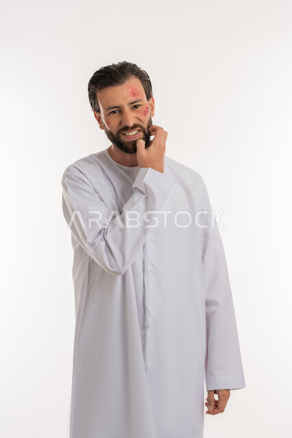 المشاكل الصحية والتهجيات، الإصابة بالحساسية الجلدية, بثور منتشرة على بشرة الوجه, بورتريه لرجل عربي خليجي اماراتي يرتدي الكندورة يقوم بالحك بإيماءات الإنزعاج والتعب, الشعور بالأوجاع والالام, خلفية بيضاء