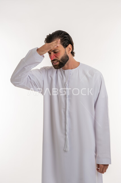 آلام الشقيقة والصداع النصفي, الشعور بالمرض وألم الرأس, الحاجة إلى العلاج والمساعده, بورتريه لرجل عربي خليجي اماراتي يرتدي الكندورة يضع يده على رأسه بإيماءات الانزعاج والتعب, خلفية بيضاء
