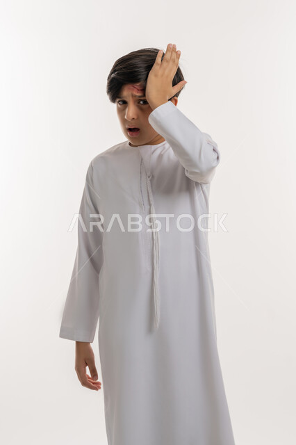 Feeling tired and exhausted, being exposed to violence and harm, needing medical care, portrait of an Arab Gulf Emirati boy wearing a kandura, putting his hand on his head with gestures of severe pain, suffering from wounds and bruises, white background