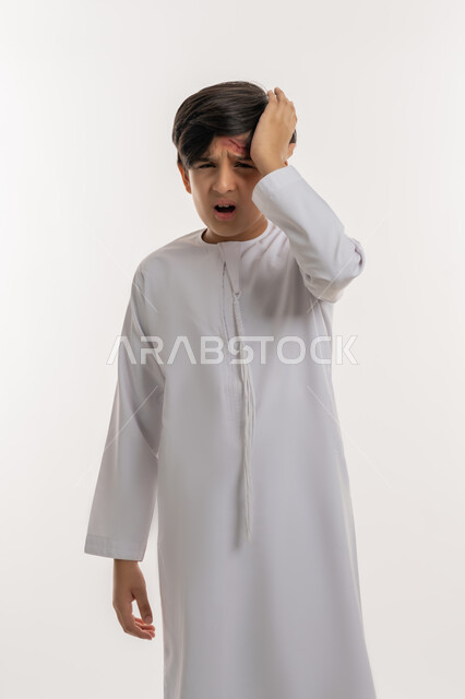 التعرض للعنف والاذى، الشعور بالتعب والارهاق، الحاجة إلى تلقي الرعاية الطبية، بورتريه لفتى عربي خليجي اماراتي يرتدي الكندورة يضع يده على رأسه  بايماءات الالم الشديد، الاصابة بالجروح والكدمات، خلفية بيضاء