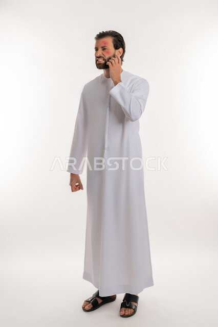 Skin allergy, pimples on face, portrait of an Arab Gulf Emirati man wearing a kandura scratching with gestures of discomfort and fatigue, health problems and spellings, feeling aches and pains, full body image, white background
